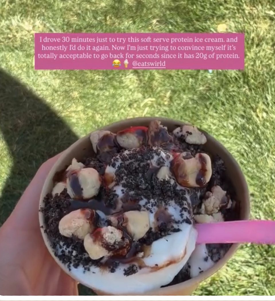 A loaded cup of Swirld soft serve with brownie and cookie toppings on the grass